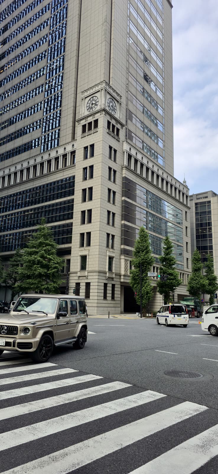 Mercedes G-Wagon parked near a stone clock tower building at a city intersection