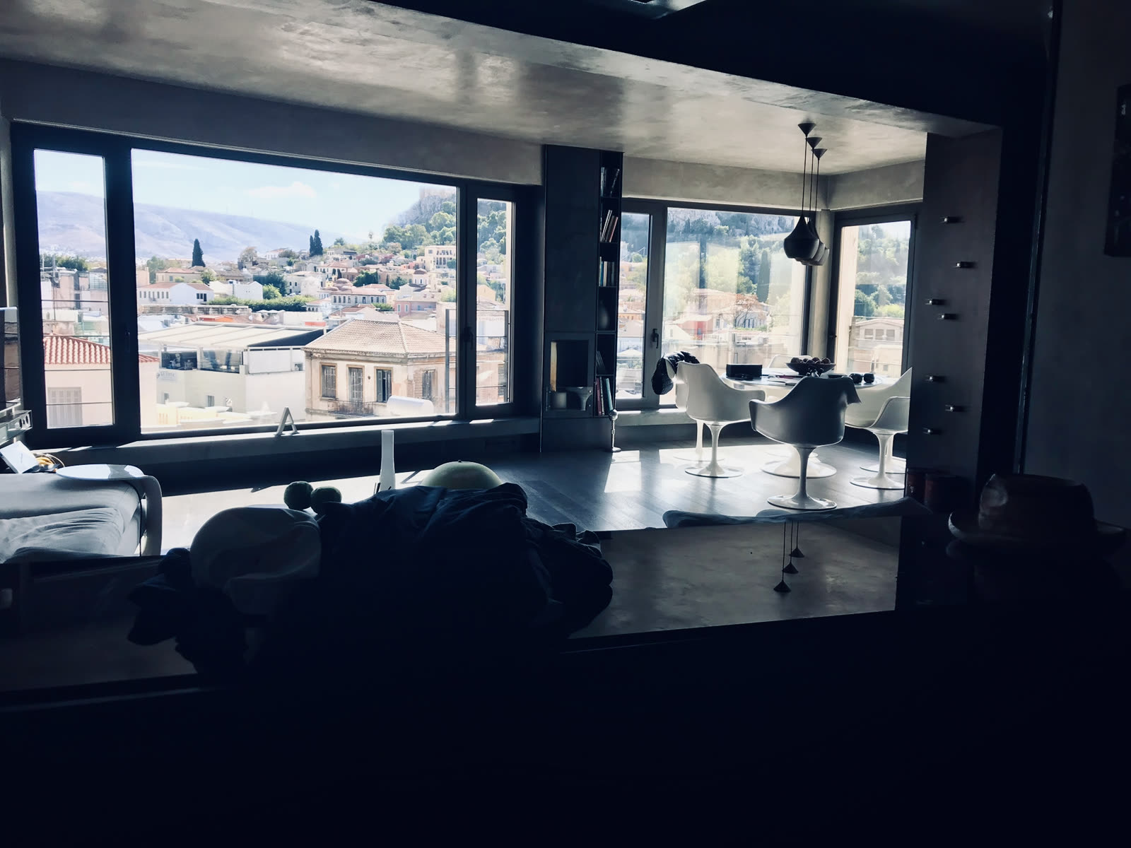 apartment living room with dining table and chairs overlooking a hillside city through floor to ceiling windows
