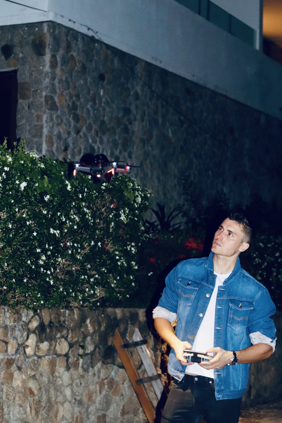 man flying a drone at night outside a stone building
